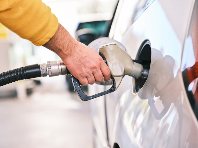 f4ubpvbjcjw-1 a man pumping gas into his car at a gas station