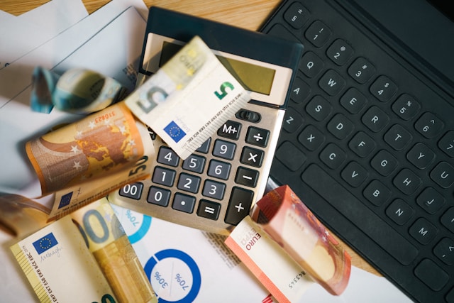 qgxjuf6-cv8-1 A calculator sitting on top of a pile of money