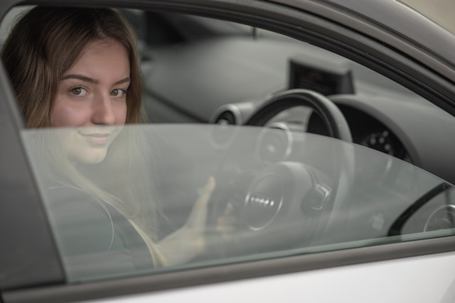 wcvsfslpg5c-1 a woman sitting in a car holding a steering wheel